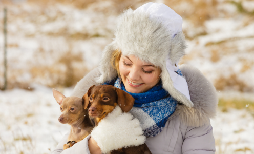 Woman holding two dogs outside in the snow